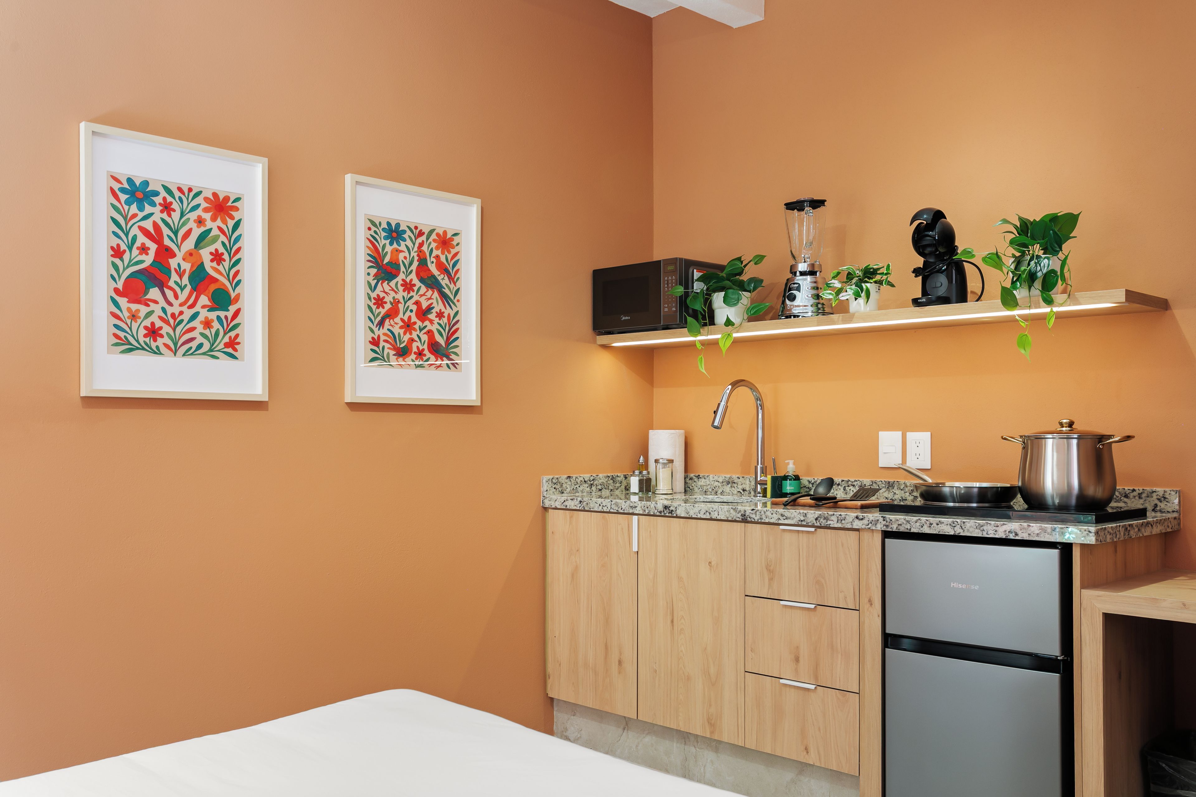Una cocina moderna con armarios de madera, lavavajillas de acero inoxidable y una encimera con cafetera y hervidor.