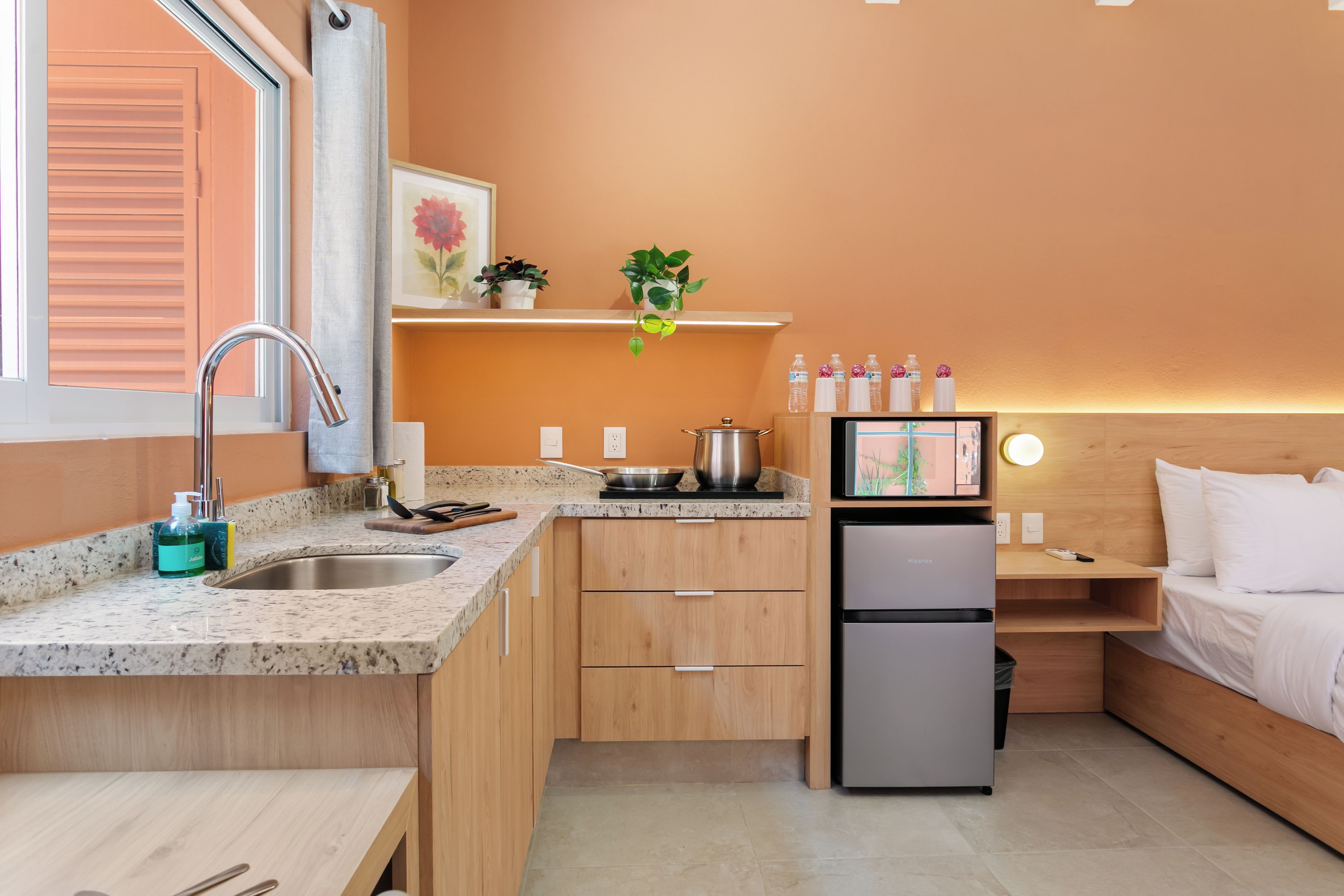 Una kitchenette compacta con pileta, hornalla y heladera, placares de madera y una pequeña mesada.