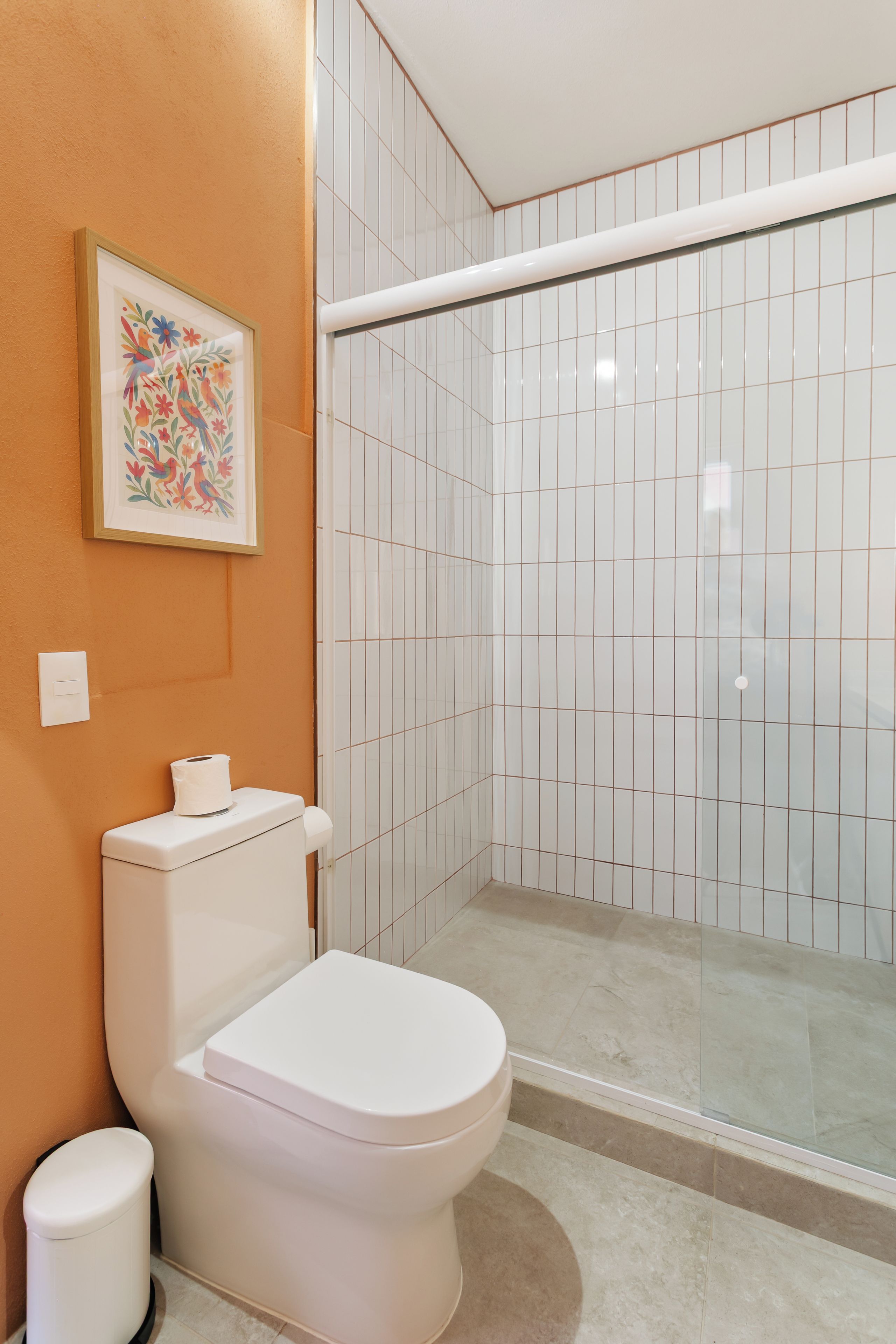 A bathroom with a toilet, a shower enclosure, and a framed artwork on the wall.