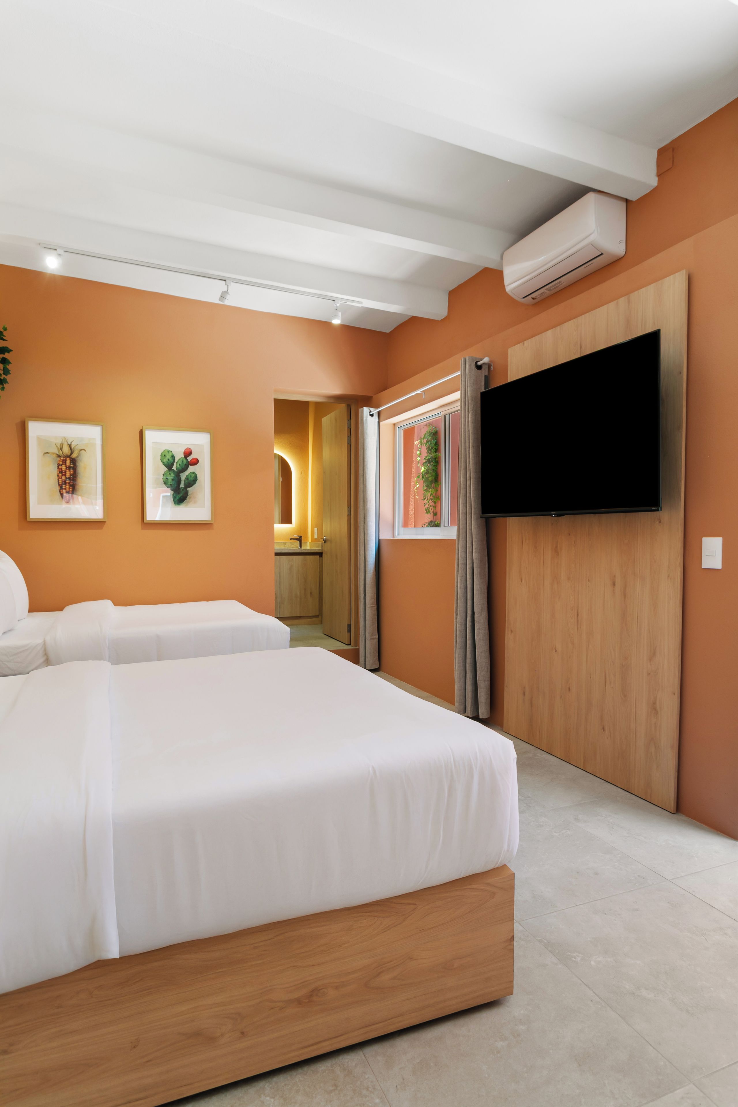 Ein Hotelzimmer mit einem großen Bett, einem Flachbildfernseher und einem durchgegangene Tür erkennbaren Badezimmer.