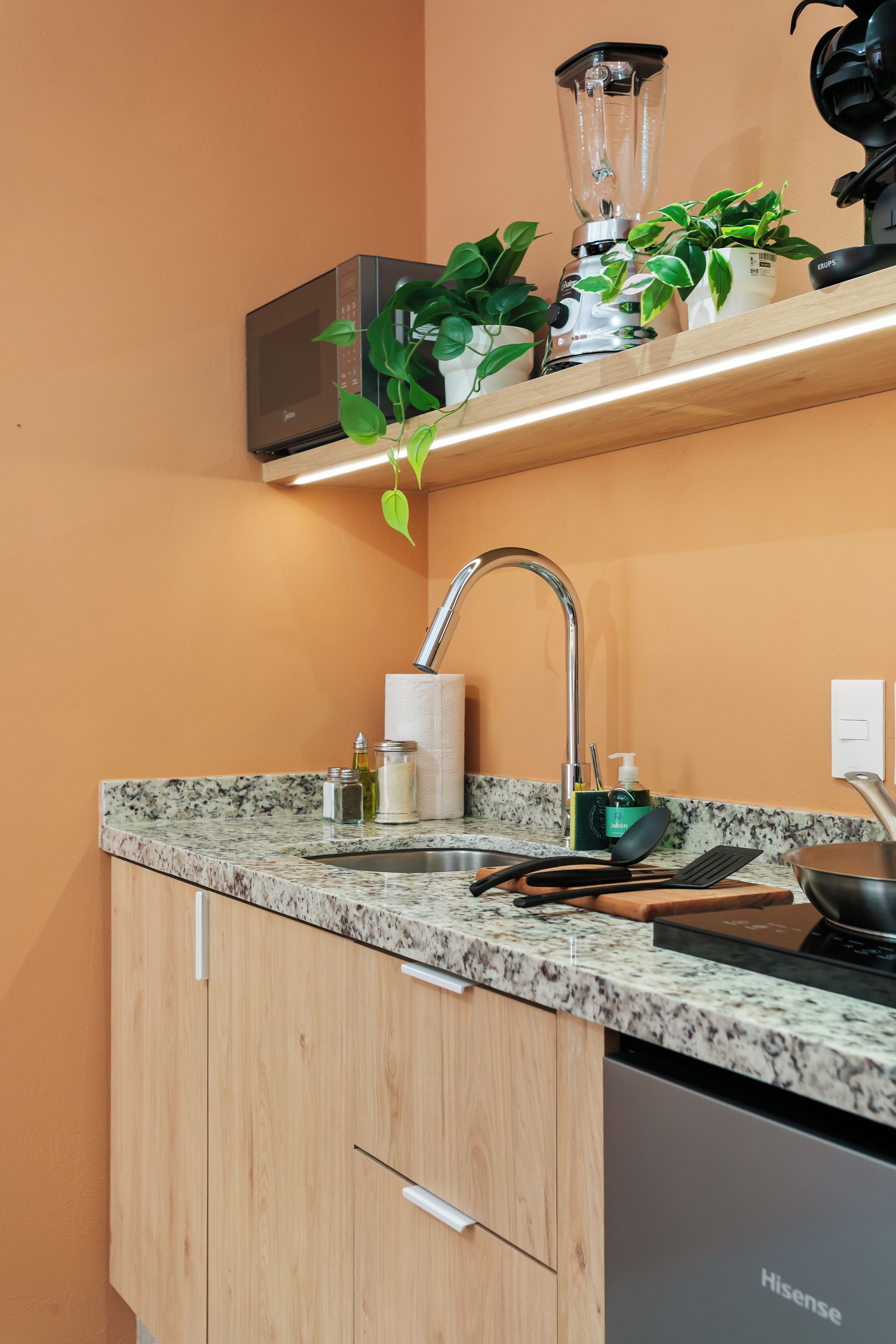 A modern kitchen with a granite countertop, a stainless steel sink, and a dishwasher.