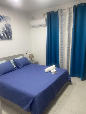 Ein Hotelzimmer mit Bett, Nachttisch, Lampe und einer Wand-Klimaanlage.