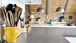 A modern kitchen with wooden beams, a central island, and a yellow utensil holder.