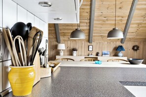 Eine moderne Küche mit Holzbalken, einer zentralen Kochinsel und einem gelben Utensilienhalter.