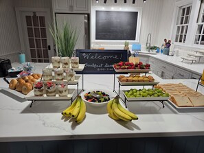 A breakfast buffet with various food items and a welcome sign. - The Castle Inn at Silver Lake (Ocracoke)