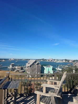 A wooden deck with a view of a harbor, including boats and buildings. - The Castle Inn at Silver Lake (Ocracoke)