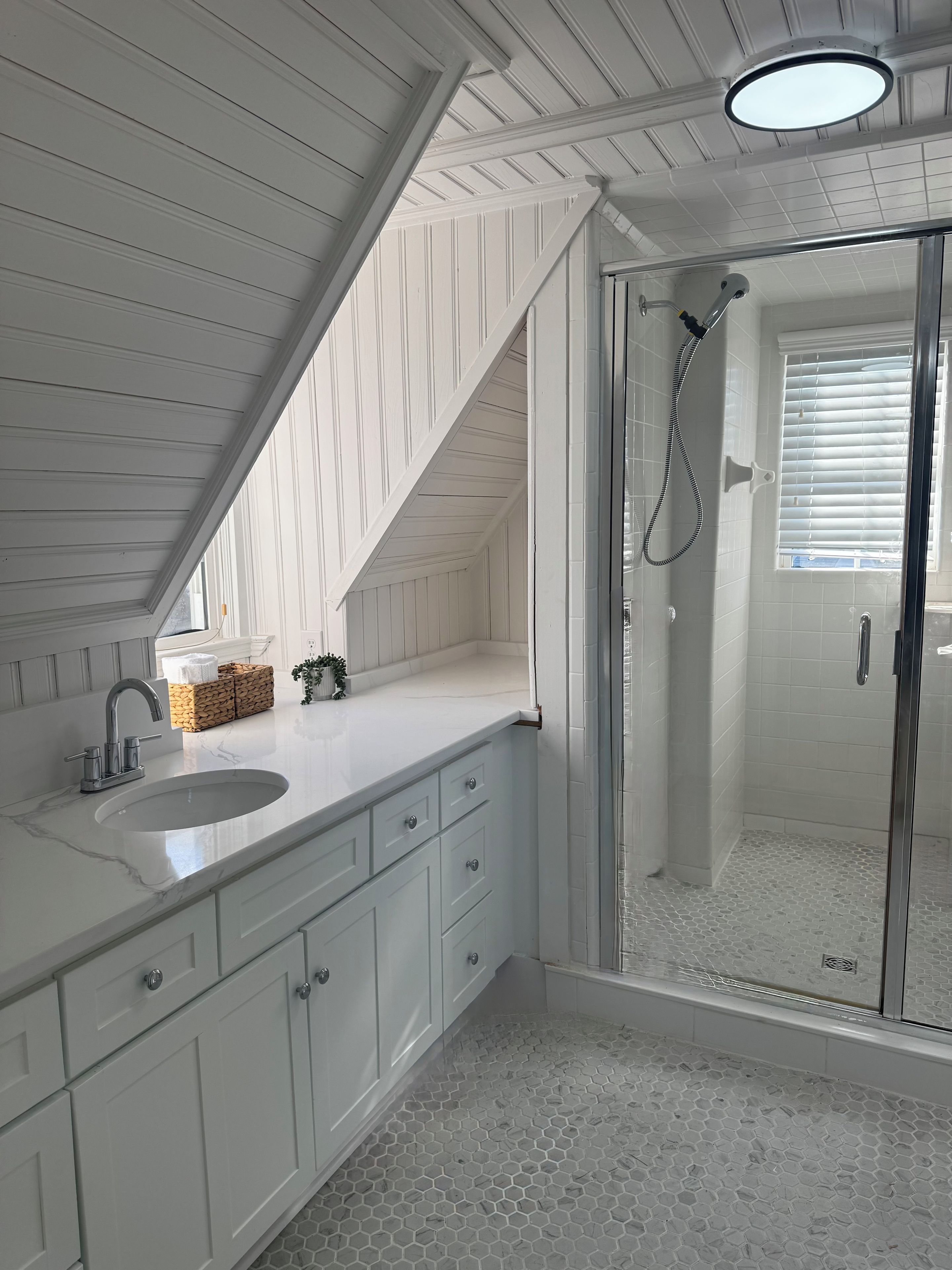 A bathroom with a white vanity, a glass shower enclosure, and a ceiling light.