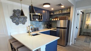 A modern kitchen with a central island, stainless steel appliances, and a bar stool seating area. - Lakeside Universal Retreat (Orlando)
