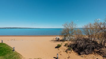 Ein Strand mit klarem, blauem Wasser, einem Sandufer und etwas Vegetation.