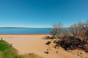Ein Strand mit klarem, blauem Wasser, einem Sandufer und etwas Vegetation.
