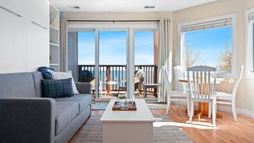 Ein modernes Wohnzimmer mit grauem Sofa, weißem Couchtisch und einem Balkon mit Sitzgelegenheit.