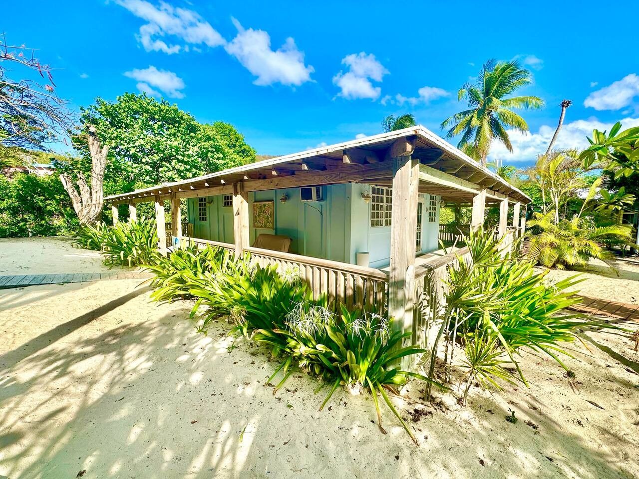 Un petit bâtiment d’un seul étage, doté d’un porche et entouré de plantes tropicales et de palmiers.