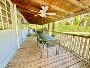 A covered outdoor area with a table and chairs, a ceiling fan, and a view of greenery. - Villa 18 Flamenco Beachfront Villas (Flamenco)