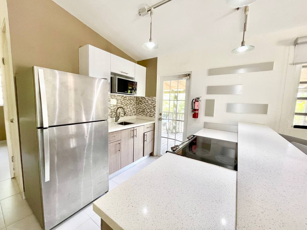 A modern kitchen with stainless steel appliances, a white countertop, and a view of the outside.