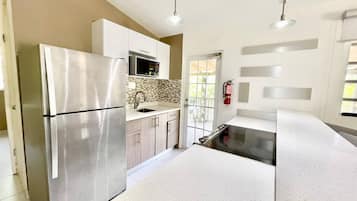 A modern kitchen with stainless steel appliances, a white countertop, and a view of the outside.