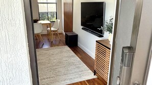 Ein modernes Wohnzimmer mit Flachbildfernseher, einem Essbereich mit Tisch und Stühlen und Holzboden.