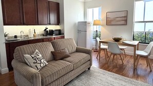 Eine moderne Küche mit dunklen Holzschränken, einem weißen Kühlschrank und einem Essbereich mit Tisch und Stühlen.