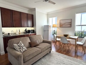 Une cuisine moderne avec des meubles en bois foncé, un réfrigérateur blanc et un coin repas comprenant une table et des chaises.