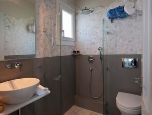 A modern bathroom with a glass-enclosed shower, a white sink, and a toilet. - Double Suite 1 balcony (Naxos)