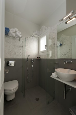 A modern bathroom with a glass-enclosed shower, a white sink, and a toilet. - Double Suite 2 balconies (Naxos)