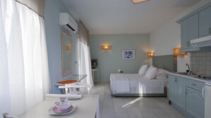 Ein kleines Hotelzimmer mit Bett, Esstisch, Küchenzeile und Bad.