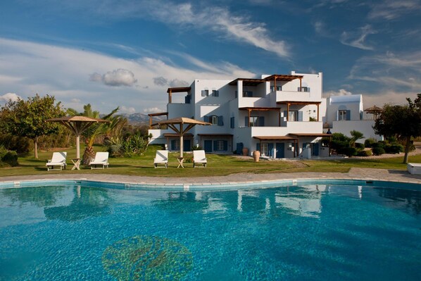 A modern multi-story building with a swimming pool, white exterior, and balconies. - Double Suite 2 balconies (Naxos)