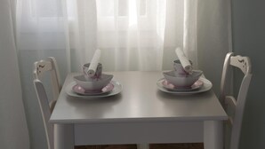 Ein weißer Esstisch mit zwei weißen Stühlen, jeweils mit einer rosa Schüssel und Untertasse.