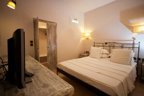 Ein Schlafzimmer mit einem Bett, Nachttischen, einem Fernseher und einer Lampe.