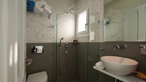 A bathroom with a glass-enclosed shower, a white sink, and a toilet. - Exclusive Apartments 1st floor (Naxos)
