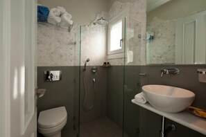 Ein Badezimmer mit einer Duschkabine, einem weißen Waschbecken und einer Toilette.