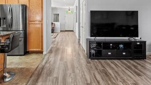 A modern kitchen with wooden cabinets, a stainless steel refrigerator, and a bar stool.