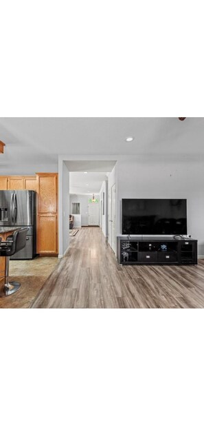 A modern kitchen with wooden cabinets, a stainless steel refrigerator, and a bar stool.