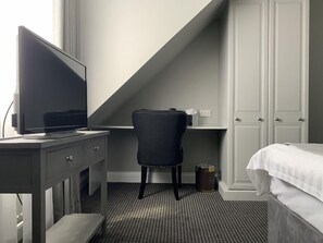 A hotel room with a desk, chair, TV, bed, and wardrobe. - Badgemore Park B B (Henley-on-Thames)