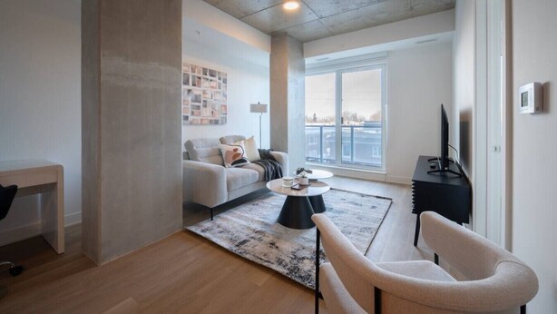 Una sala de estar moderna con sofá, mesa de centro y mueble para televisión.