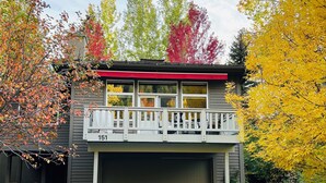 Une maison à deux étages avec un garage, un balcon doté de balustrades blanches et le numéro « 151 » peint sur la porte du garage.