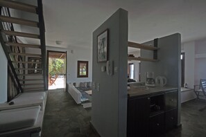 Ein modernes Interieur mit Treppe, einer Couch, einer Küchenzeile und einem Esstisch.