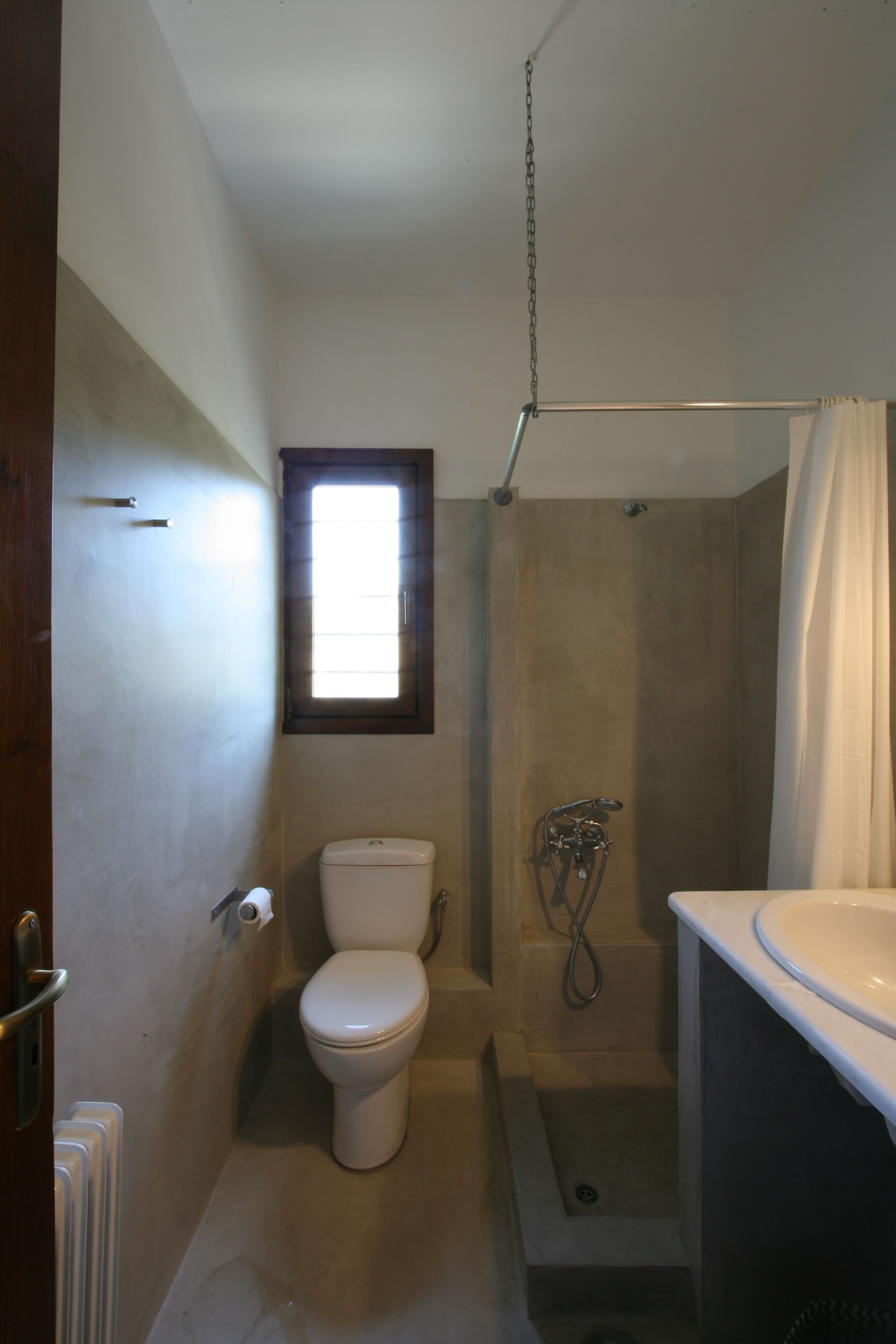 A compact bathroom with a toilet, shower, and sink.
