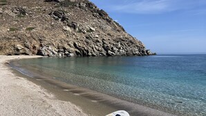 Ein Kajak an einem Kiesstrand mit klarem Wasser und einer felsigen Klippe im Hintergrund.
