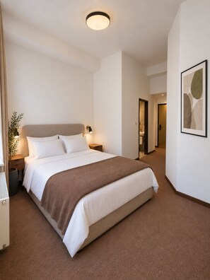 A hotel room with a large bed, bedside tables, a nightstand, a wall-mounted lamp, a potted plant, and a framed abstract artwork. - VILDSTEJN Private Wellness Apartments (Karlovy Vary)