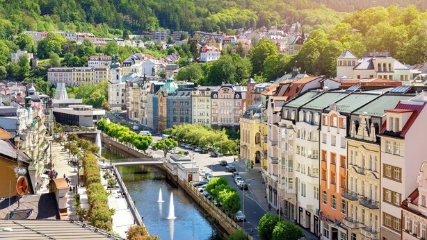 A riverside cityscape with historic buildings, a bridge, and a canal.