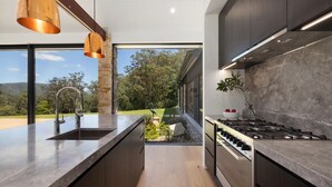 Cocina moderna con una columna de piedra, un lavamanos de acero inoxidable y un amplio ventanal con vistas a un jardín.