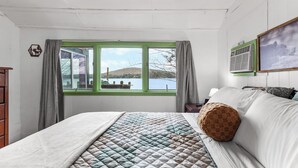 Una camera da letto con un letto, una finestra con tende, un condizionatore d'aria a parete e un quadro.