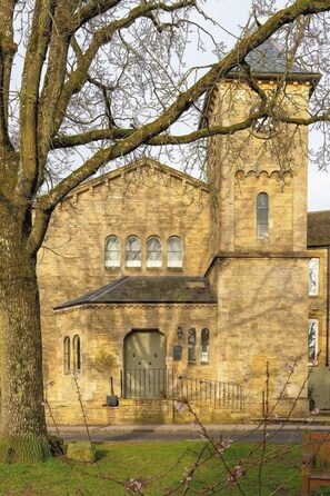 A stone building with a central tower, arched windows, and a gated entrance. - Charming Historic Apartment in Stow-on-the-Wold (Stow-on-the-Wold)