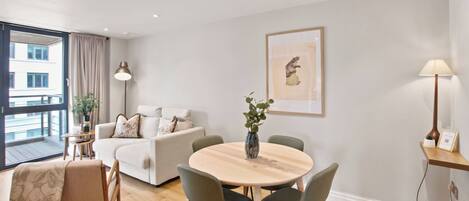 A modern living room with a round wooden table, two sofas, a coffee table, and a dining area.