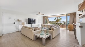 Ein modernes Wohnzimmer mit einer Couch, einem Couchtisch und einem an der Wand befestigten Fernseher.