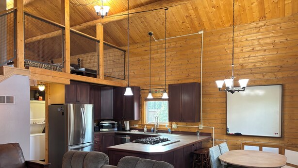 Une cuisine spacieuse aux murs en bois, dotée d’un grand îlot central et d’appareils électroménagers modernes.
