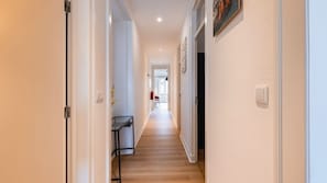 A narrow hallway with a wooden floor, white walls, and a door on the right. - Classy 3-Bedroom Lisbon Apartment by LovelyStay (Lisboa)