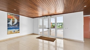 Eine geräumige Lobby mit Holzboden, einer großen Glasdoor, die nach draußen führt, und einem Gemälde einer Möwe an der Wand.