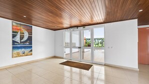 Eine geräumige Lobby mit Holzboden, einer großen Glasdoor, die nach draußen führt, und einem Gemälde einer Möwe an der Wand.