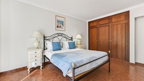 Ein Schlafzimmer mit einem Bett, Nachttischen, einem Holzschrank und einem gerahmten Bild an der Wand.